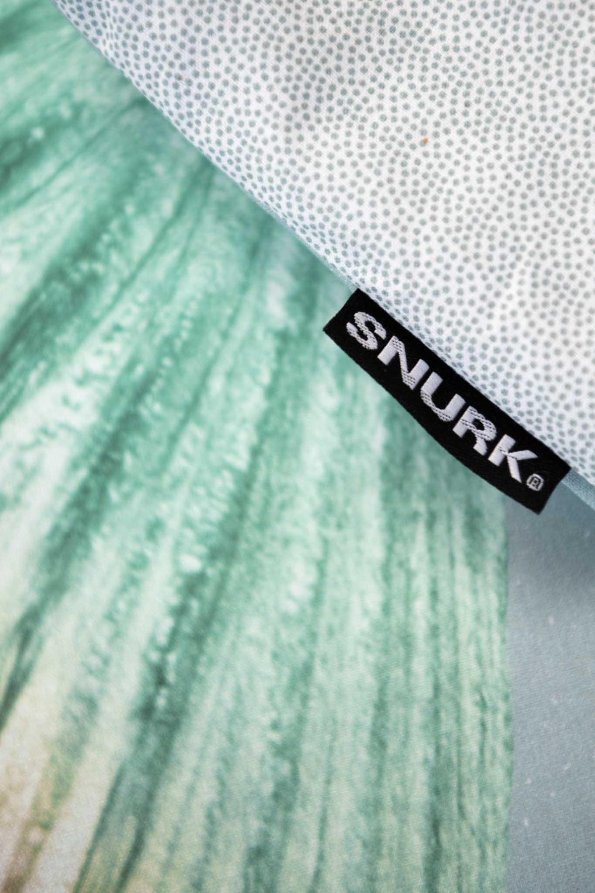 Detail van dekbedovertrek Mermaid met groene staartprint, zwart merklabel en een omgeslagen rand met stipjes.