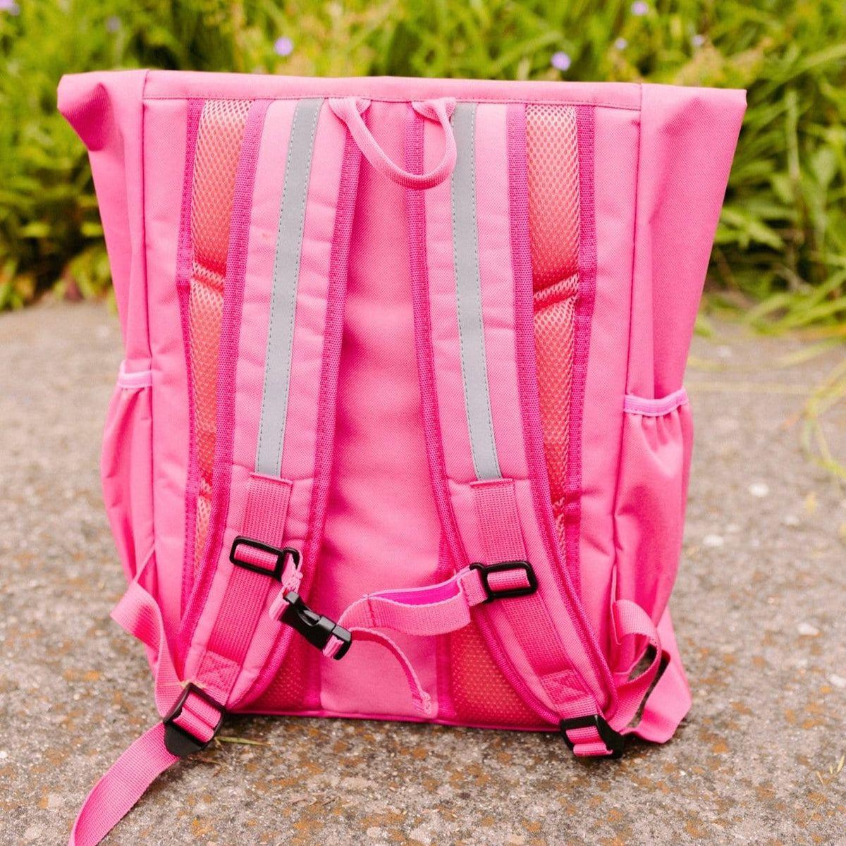 Achterkant van de roze Flashbag Lou-rugzak met verstelbare schouderbanden, reflecterende stroken en borstclip.
