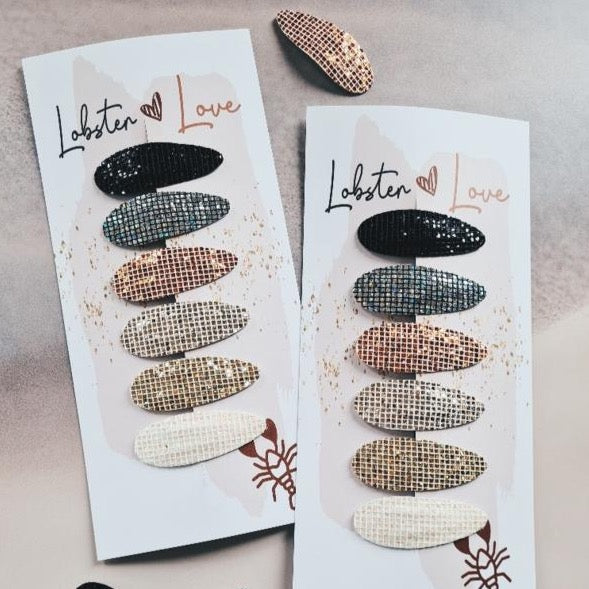 Twee kaartjes met elk zes Holiday Season-haarspeldjes in zwart, grijs, koperkleur, goudkleur en wit.