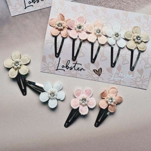 Haarspeldjes Pastel Flowers met bloemen in zachte tinten, vijf op een kaart en vier los ernaast.