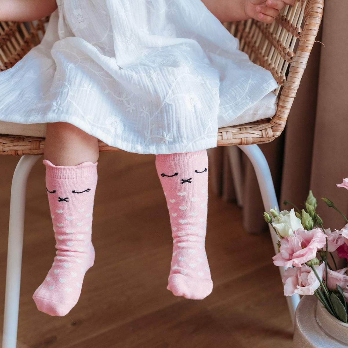 Roze Lilly a Pinky Kitty kniekousen met kattengezichtjes en witte hartjes, gedragen onder een witte jurk.