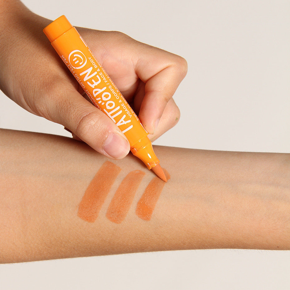 Hand tekent drie oranje strepen op een onderarm met de oranje tattoopen