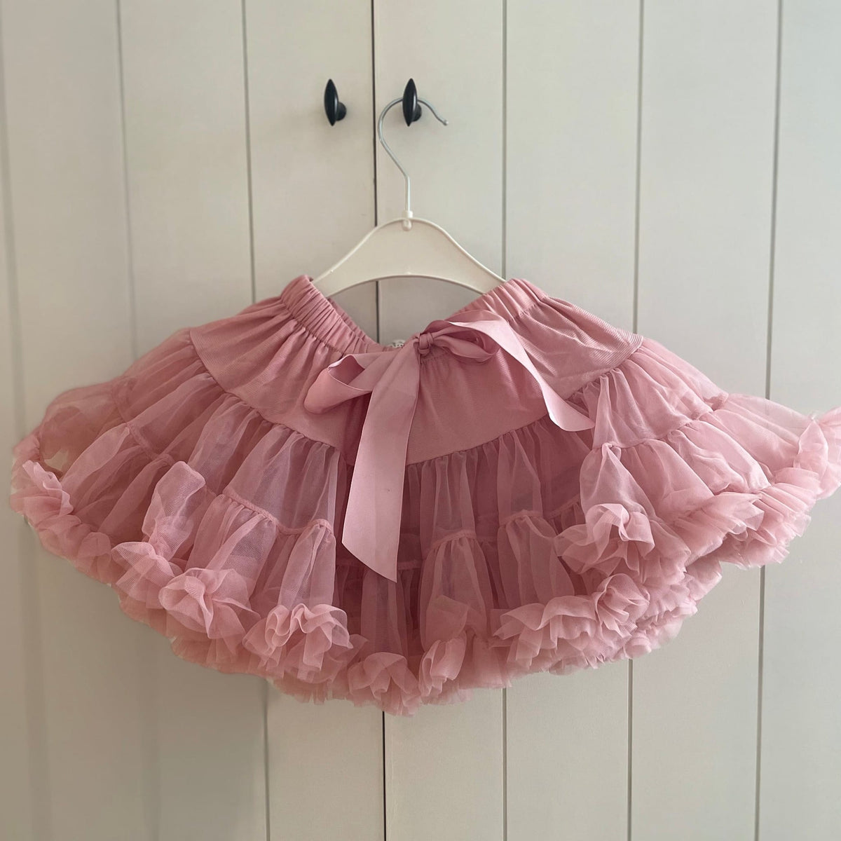 Roze Loli tutu rok met strik en uitwaaierende ruches aan een witte kledinghanger.