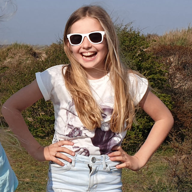 Meisje draagt de witte Koolsun Wave zonnebril buiten, met haar handen op haar heupen