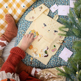 Kind bekijkt accessoires op de open konijnenadventskalender, met genummerde zakjes ernaast.