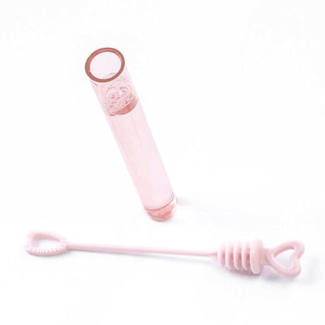 Geopend roze bellenblaasbuisje met daarnaast een blaasstokje met hartvormige ring en dop.
