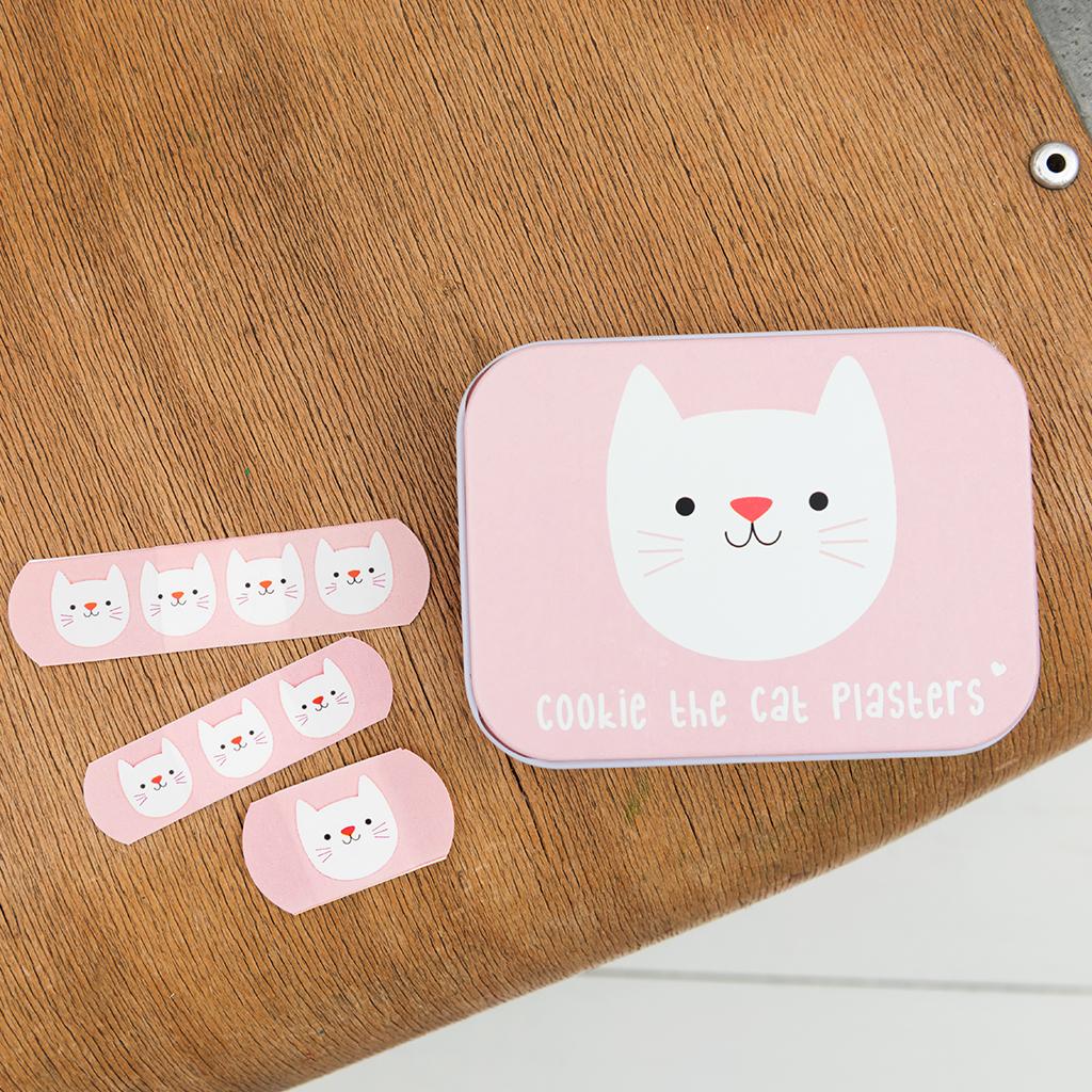 Roze Cookie The Cat-pleisterblikje met drie roze kattenpleisters ernaast op een houten tafel.