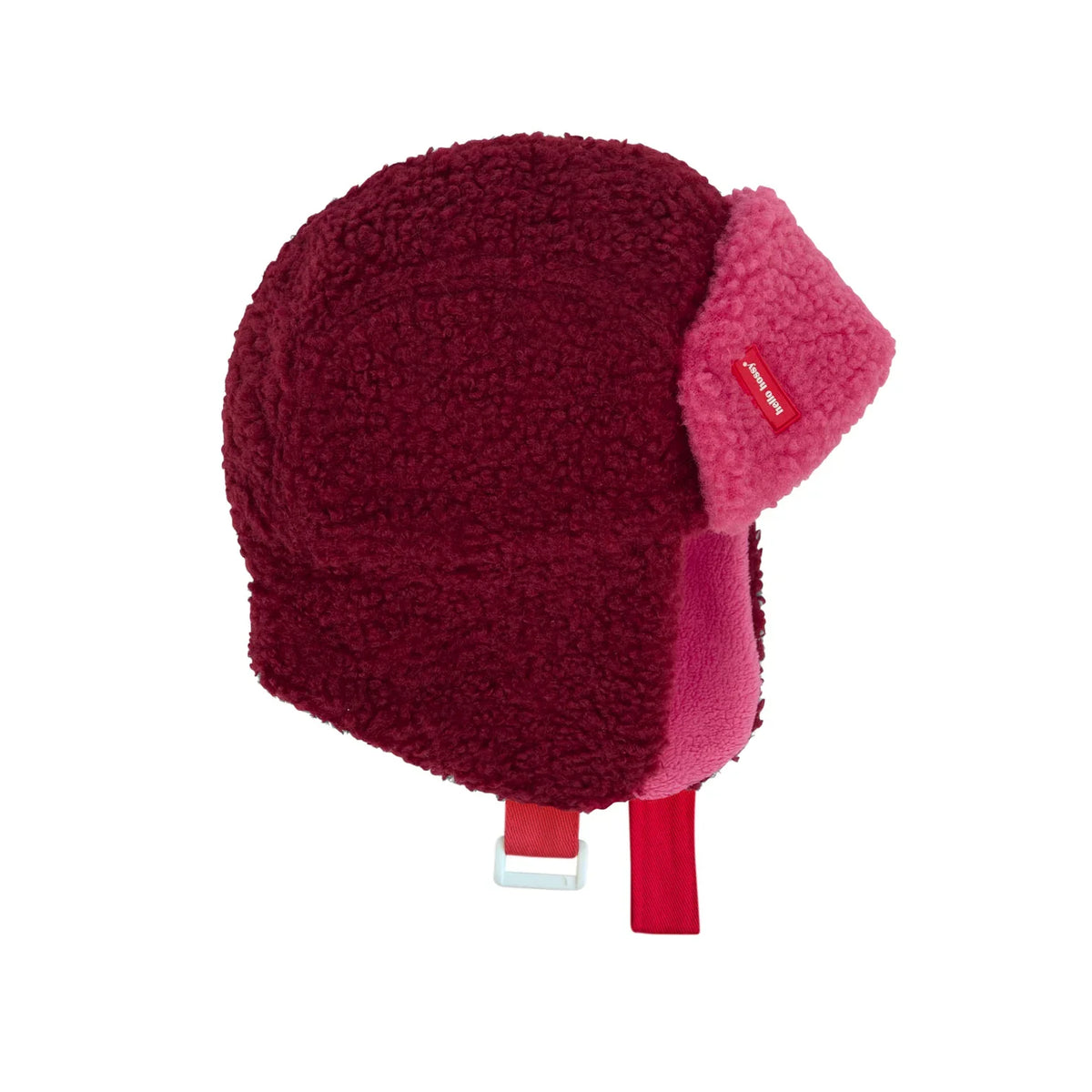 Cozy Tara chapka in bordeauxrood en roze met oorkleppen en verstelbare kinband, van opzij gezien.