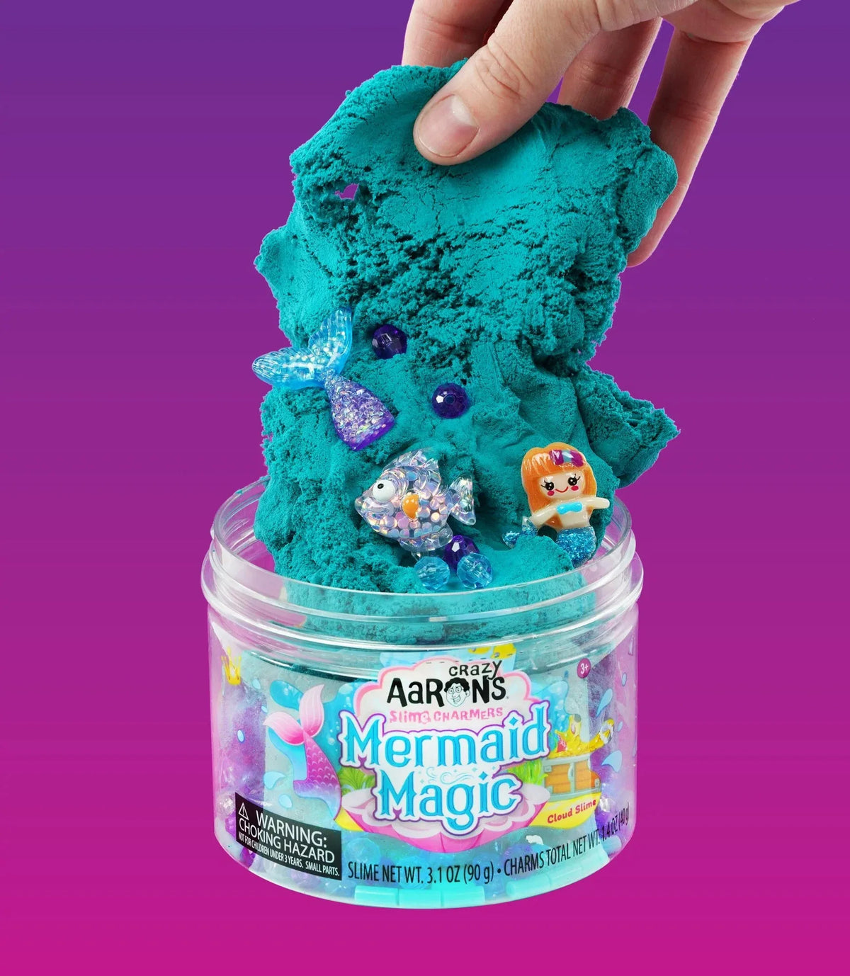 Een hand trekt Mermaid Magic wolkenslijm met een zeemeermin, vis en zeemeerminstaart omhoog uit de pot.