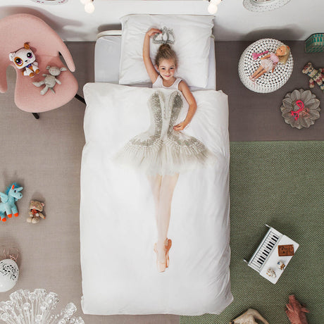 Meisje onder een wit ballerina-dekbedovertrek, met haar hoofd boven de tutuprint en een arm boven haar hoofd.