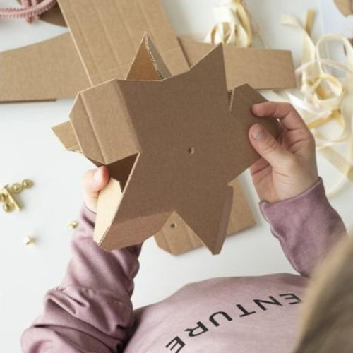 Kind houdt een bruine kartonnen ster vast voor de toverstaf uit de DIY-feeënset.