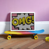 Dot On omg stickerposter in een witte lijst op een kleurrijk skateboard tegen een roze muur