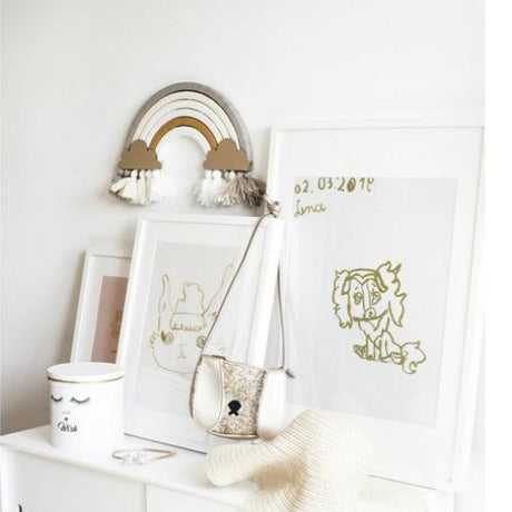 DIY regenboog Nude aan de muur boven een witte kast met ingelijste tekeningen en accessoires.