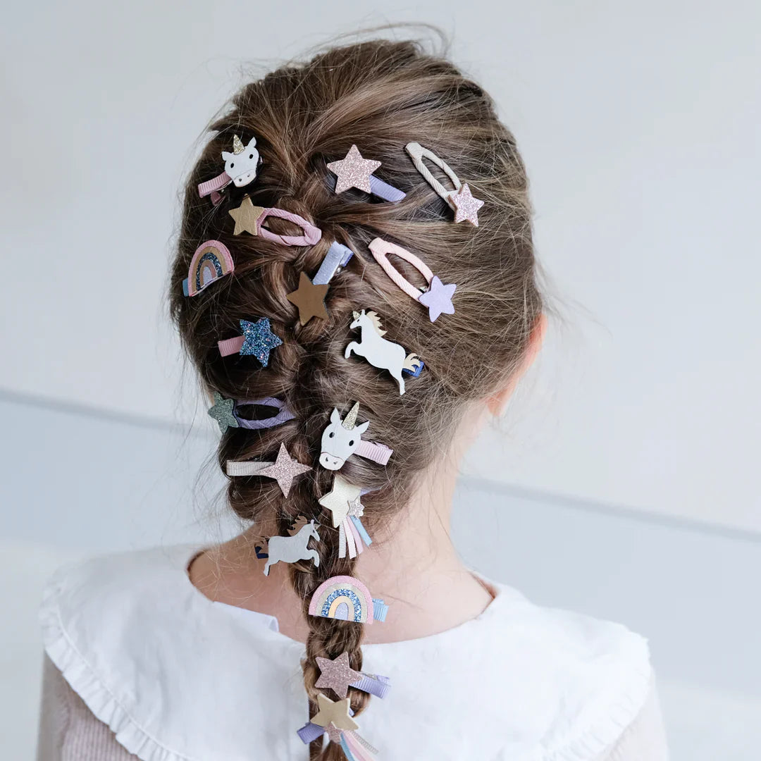Minihaarclips met eenhoorns, sterren en regenbogen in de vlecht van een kind, van achteren gezien.