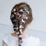 Minihaarclips met eenhoorns, sterren en regenbogen in de vlecht van een kind, van achteren gezien.
