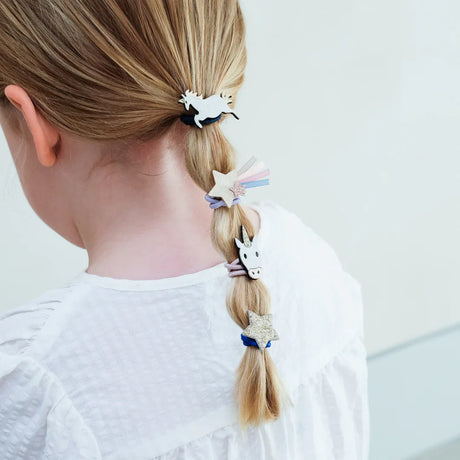 Eenhoorn- en sterhaarelastiekjes met glitter en pastelkleurige lintjes in de blonde paardenstaart van een kind.