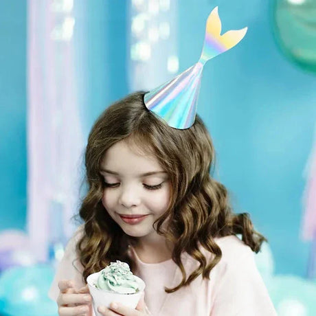 Meisje met een glanzend zeemeerminfeesthoedje met staartvin, met een cupcake in haar handen.