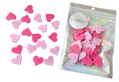 Hartvormige fietskralen in lichtroze en fuchsia, los naast een glanzend zakje met hartjes.