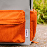 Detail van de grijze Flashbag Charlie rugzak met oranje ribfluwelen voorvak en zijvak.
