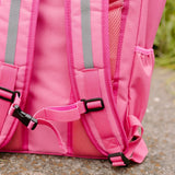 Achterkant van de roze Flashbag Lou-rugzak met verstelbare schouderbanden, reflecterende stroken en borstclip.