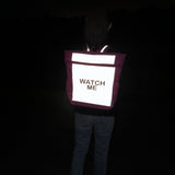 Flashbag Lou-rugzak op de rug van een kind in het donker, met fel oplichtend reflecterend voorpaneel.