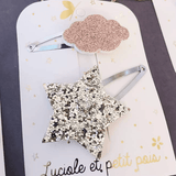 Detail van haarspelden met een goudkleurige glitterster en een rosékleurige glitterwolk op kliksluitingen.
