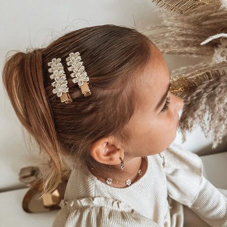 Meisje met twee Golden Flowers haarspeldjes met goudkleurige bloemen naast haar paardenstaart.