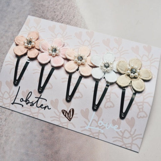 Vijf zwarte haarspeldjes op een kaart, met pastelkleurige bloemen, kraaltjes en een strasssteentje in het hart.