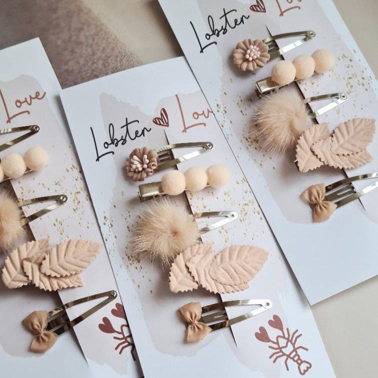 Drie sets Summer Vibes haarspeldjes op kaartjes, met roze bloemen, bolletjes, pluizige pompons, blaadjes en strikjes.
