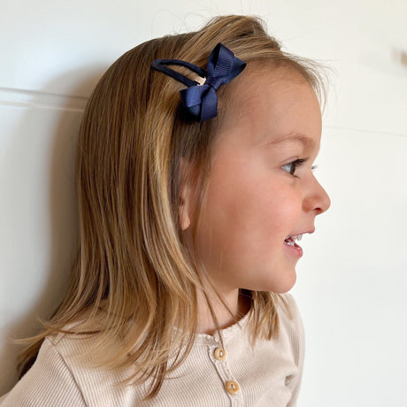 Meisje met een marineblauw haarspeldje met strik aan de zijkant van haar haar.