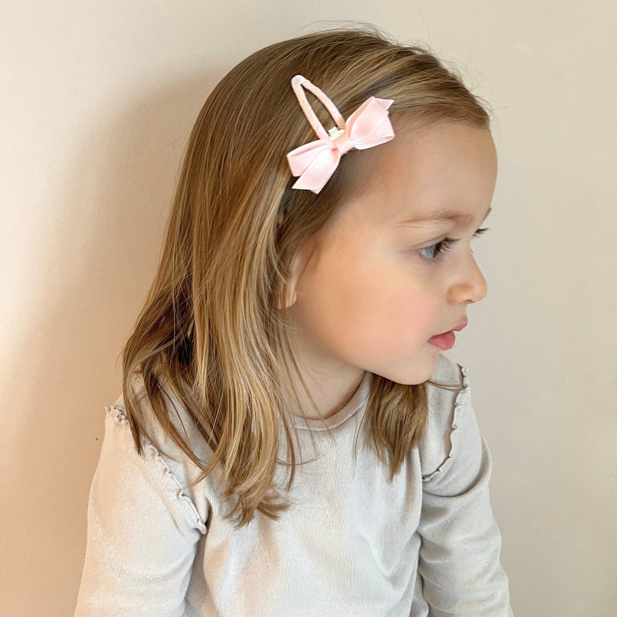 Meisje met een lichtroze haarspeldje met strik aan de zijkant van haar haar.