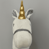 Hoppy Horse Unicorn stokpaard van voren met witte kop, goudkleurige hoorn, grijze binnenoren en grijs halster.