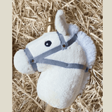 Witte kop van het Hoppy Horse Unicorn stokpaard op stro, met witte manen, grijs halster en goudkleurige hoorn.