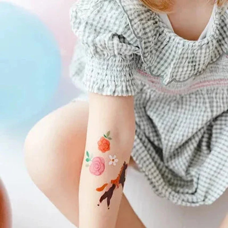 Kindertattoos met een paard en roze en oranje bloemen op de onderarm van een kind.