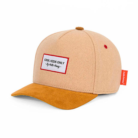 Hello Hossy Melton Creamy pet in beige met okerkleurige klep en rood omrand embleem, schuin van voren.