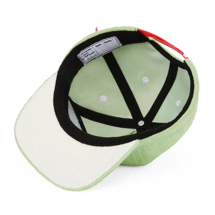 Binnenkant van de lichtgroene Mini Kiwi-pet van Hello Hossy met zwarte banden en een lichte onderkant van de klep.