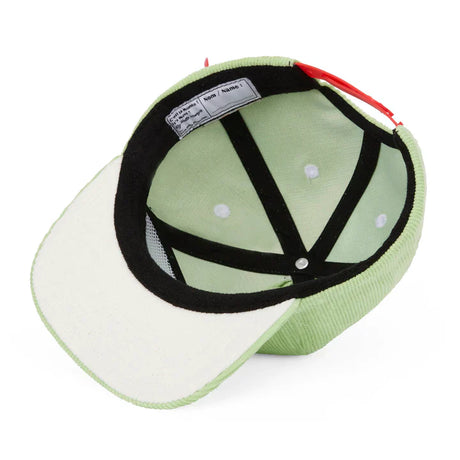 Binnenkant van de lichtgroene Mini Kiwi-pet van Hello Hossy met zwarte banden en een lichte onderkant van de klep.