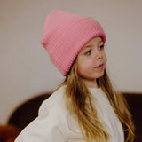 Kind met roze Flow Pink muts van Hello Hossy en een wit shirt, van opzij gezien.
