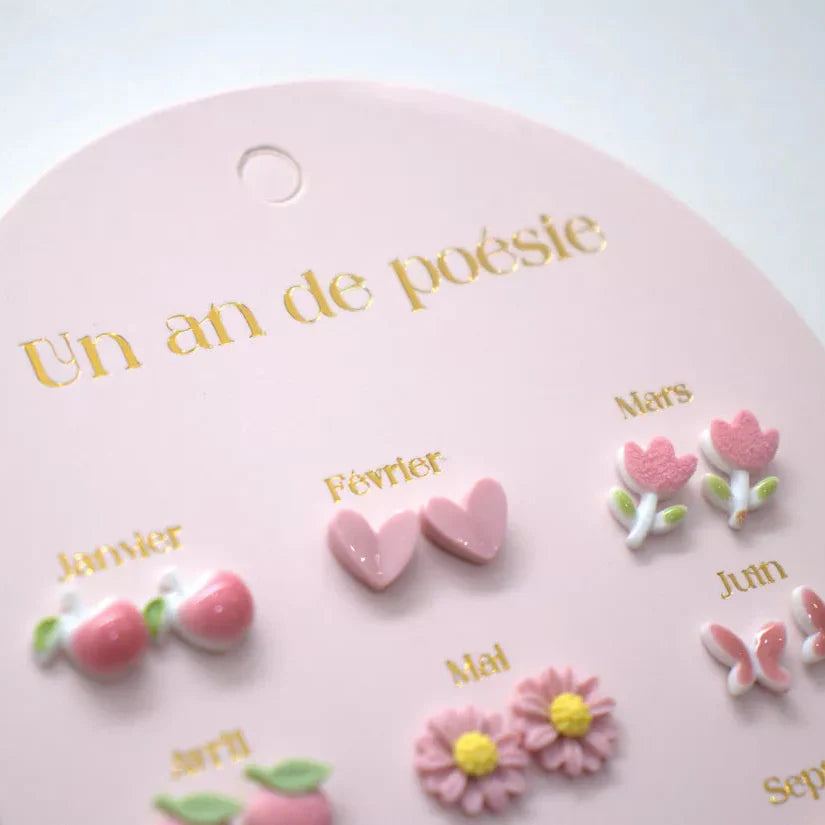 Detail van roze oorbellen op een kaart, met kersen, hartjes, tulpen en bloemen met gele hartjes.