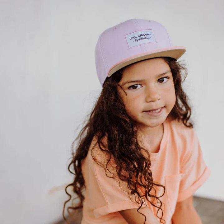 Kind met een lila Hello Hossy Mini Purple pet met roze klep en een perzikkleurig shirt.