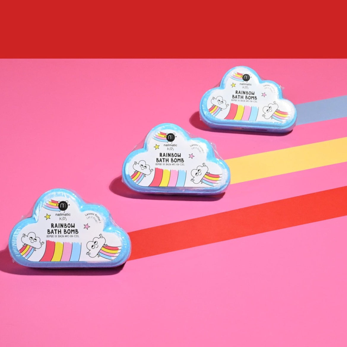 Drie blauwe regenboogbruisballen in wolkvorm met kleurrijke etiketten op een roze achtergrond met gekleurde strepen.
