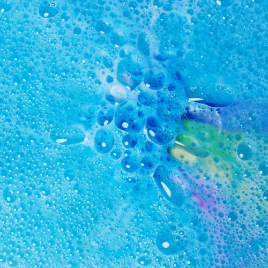 Detail van blauwe bubbels met groene, gele en roze kleursporen van de oplossende regenboogbruisbal.