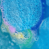 Blauw badwater met schuimende bubbels en roze, gele en groene kleurbanen van de regenboogbruisbal.