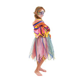 Kind in regenboogjurk met kleurrijke vleugels om de schouders en een bijpassend masker, van opzij gezien.