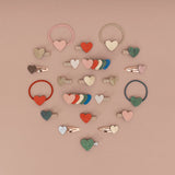 Retro Hearts miniclips tussen andere haarclips en haarelastieken met hartjes op een roze achtergrond.
