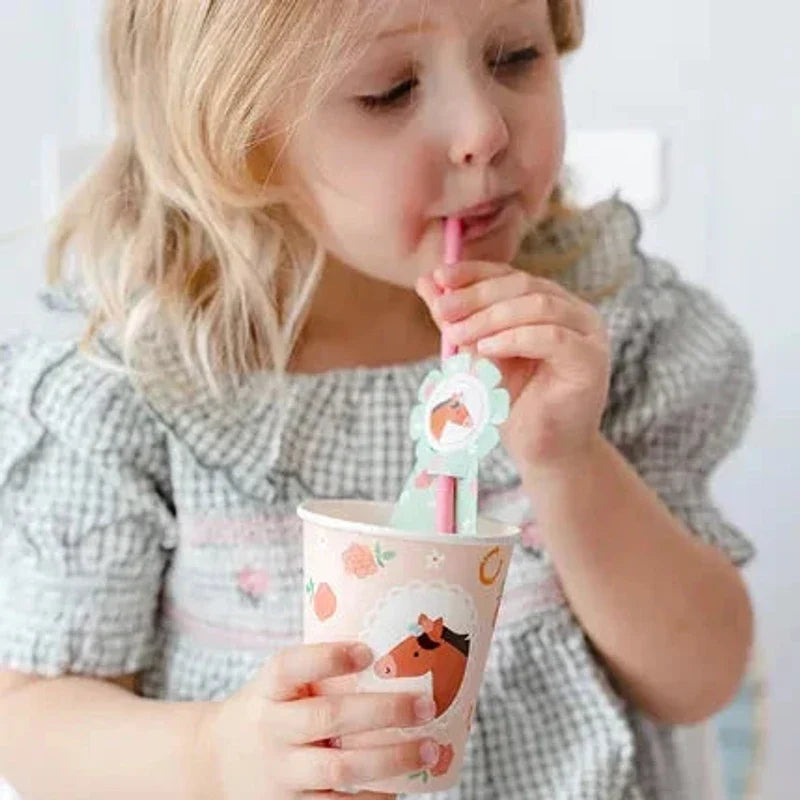 Kind drinkt uit een beker met paardenprint door een roze rietje met mintgroene paardenrozet.
