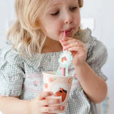 Kind drinkt uit een beker met paardenprint door een roze rietje met mintgroene paardenrozet.