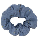 Grijsblauwe scrunchie met gouden spatjes op een witte achtergrond