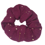 Donkerpaarse scrunchie van hydrofiel katoen met gouden spatjes.