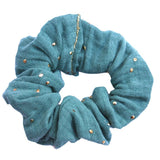 Petrolblauwe scrunchie van hydrofiel katoen met gouden spatjes.